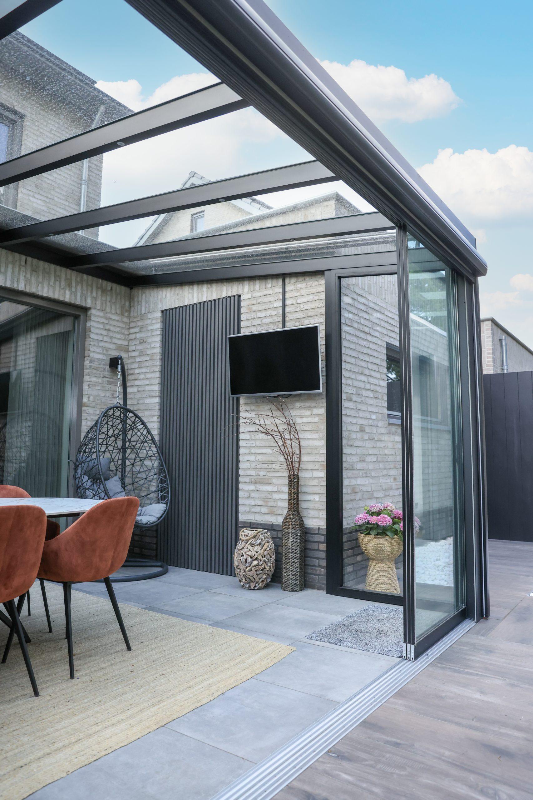 Tuinkamer met glazen dak, eettafel en hangstoel