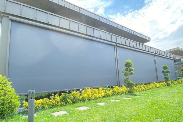 Gesloten zonwerende screens bij een woning met grote groene tuin