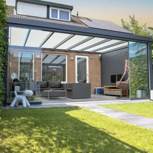 Veranda aan huis met glazen dak in een groene tuin