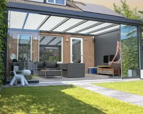 Veranda aan huis met glazen dak in een groene tuin