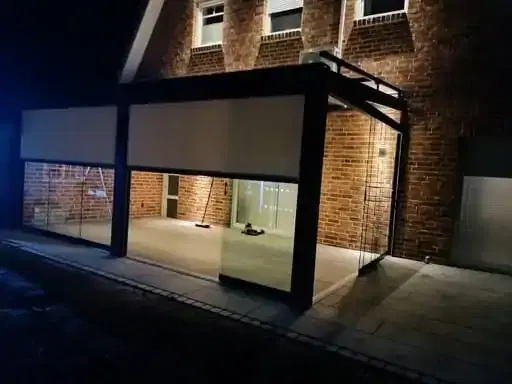 Half geopende zonwerende screen op een veranda in de avond