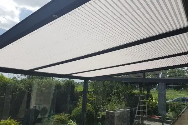 Plisse zonwering op het glazen dak van een overkapping