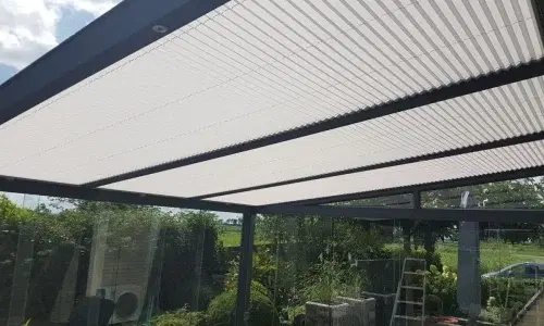 Plisse zonwering op het glazen dak van een overkapping