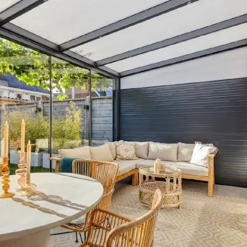 Warme tuinkamer gevuld met houten meubels en met glazen dak