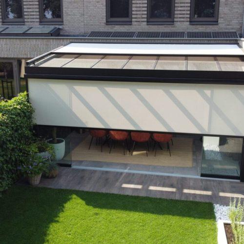 Half gesloten zonwering op een veranda met glazen dak