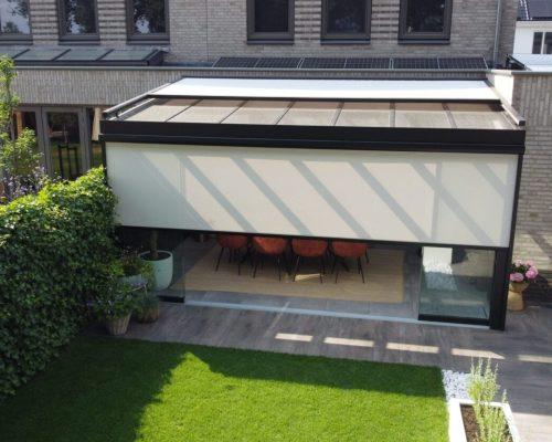 Half gesloten zonwering op een veranda met glazen dak